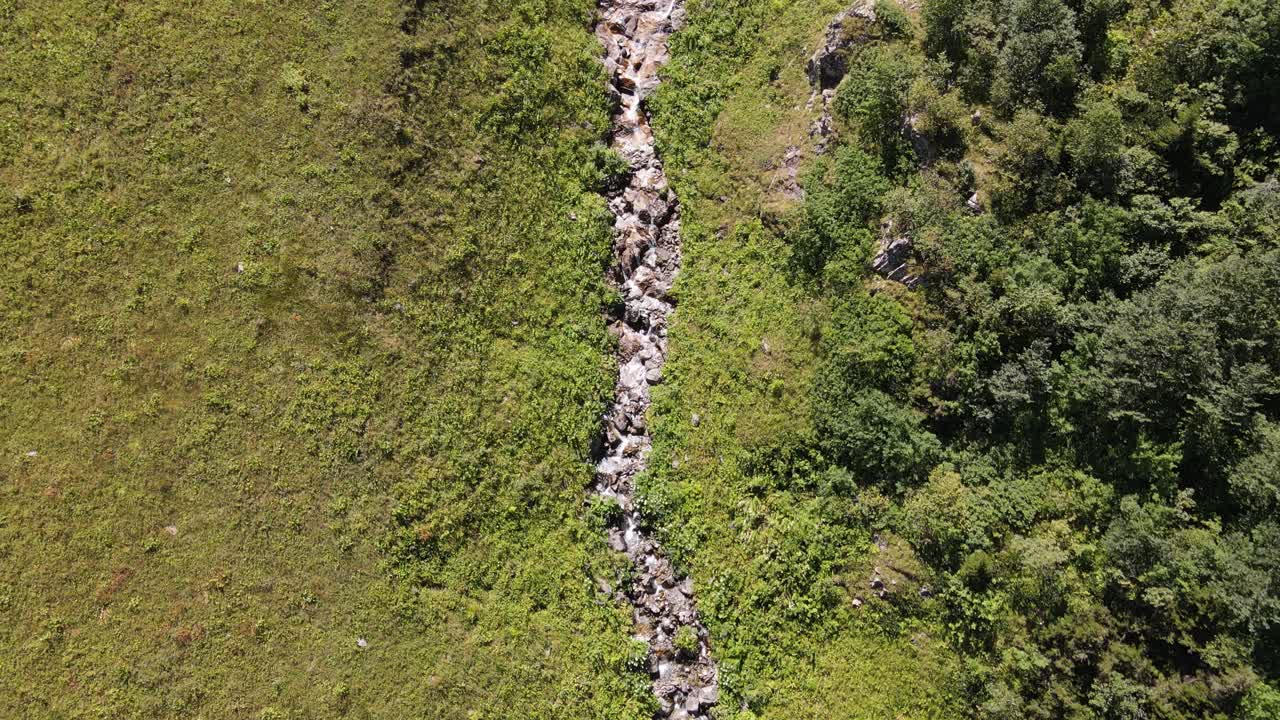 agua que fluye desde el arco entre las montañas, vista del arroyo desde arriba