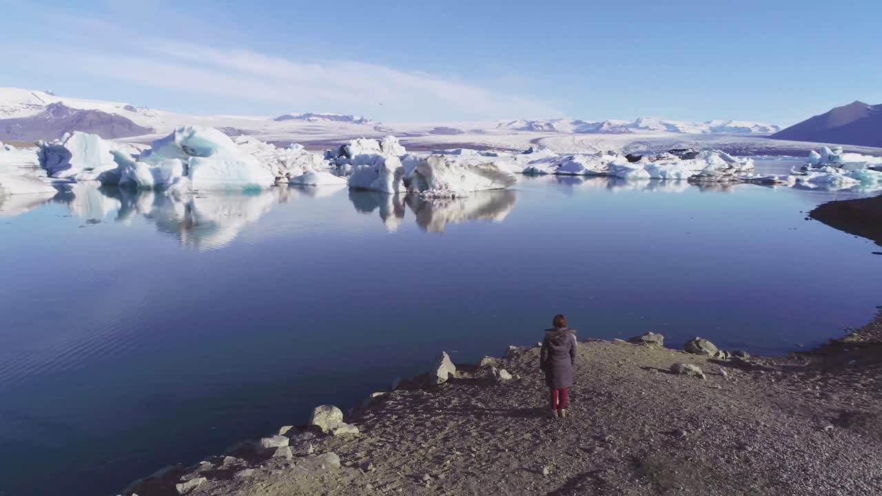 jokulsarlon glacier lagoon iceland 4에서 북극의 빙하 석호 해안을 따라 서있는 여성의 공중