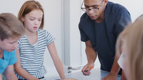 estudiantes con maestro masculino en la clase de codificación de computadoras después de la escuela aprendiendo a construir vehículos robóticos