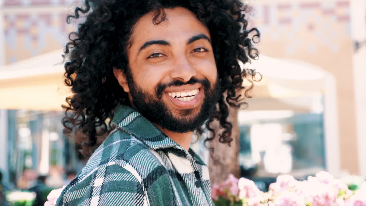 hombre con cabello rizado sonriendo al aire libre