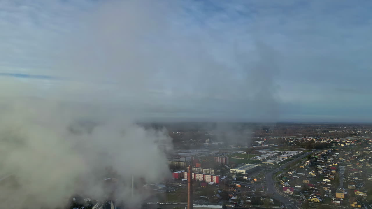 Revealing township from smoke of industrial factory, aerial drone view
