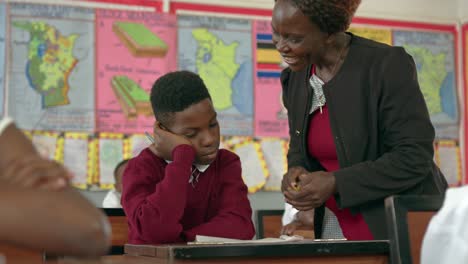 Female Teacher Helping Student In Class At School In Uganda - Close Up