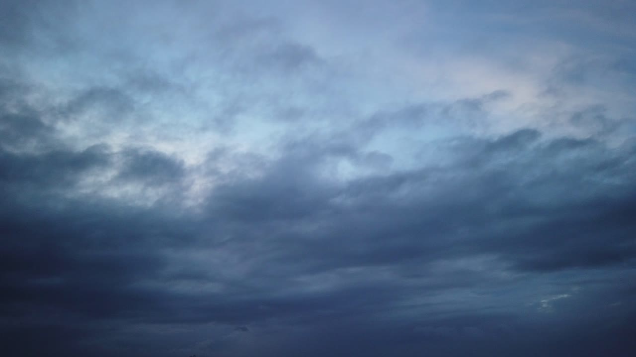 Rushing low and midlevel cloud hyperlapse over an ocean beach, sunrise, blue hour, dark