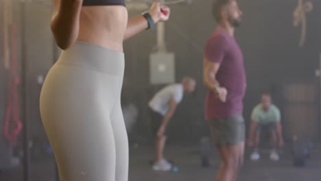 Midsection-of-diverse-woman-and-man-training-at-gym-jumping-rope,-in-slow-motion