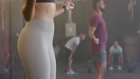 sección media de una mujer y un hombre diversos entrenando en un gimnasio saltando la cuerda, en cámara lenta