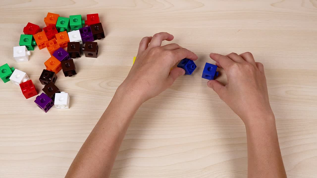 Hands assembling cubes on a wooden table