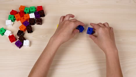 hands assembling cubes on a wooden table