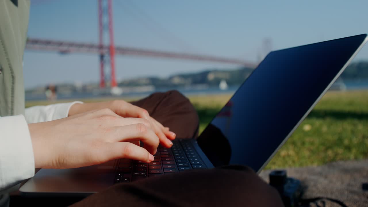 다리 근처 에 있는 공원 에서 노트북 을 사용 하고 있는 사람
