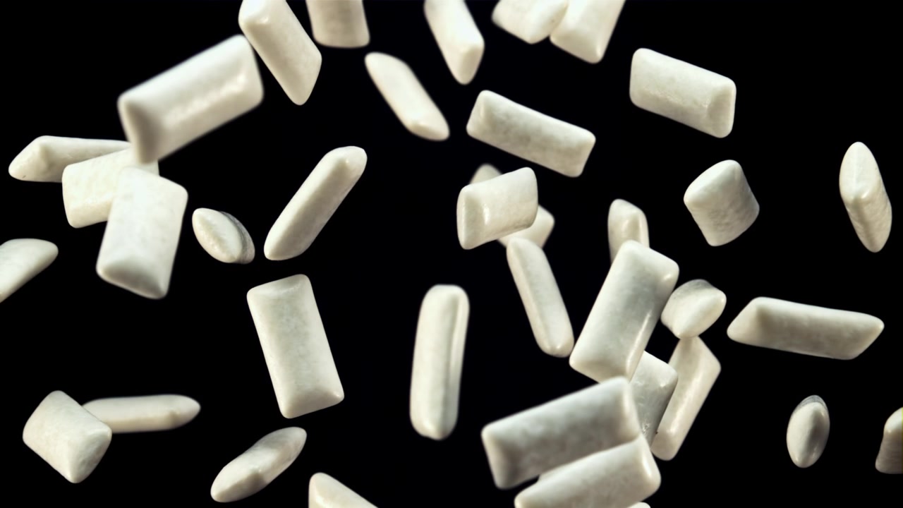 Pezzi di gomma da masticare bianca che galleggiano e cadono su sfondo nero