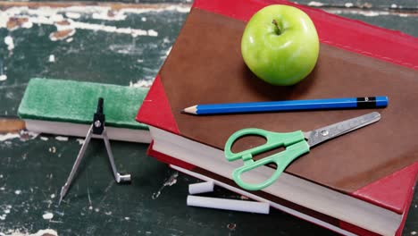 Green-apple-on-book-stack-with-school-supplies