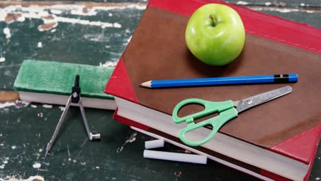 manzana verde en la pila de libros con suministros escolares