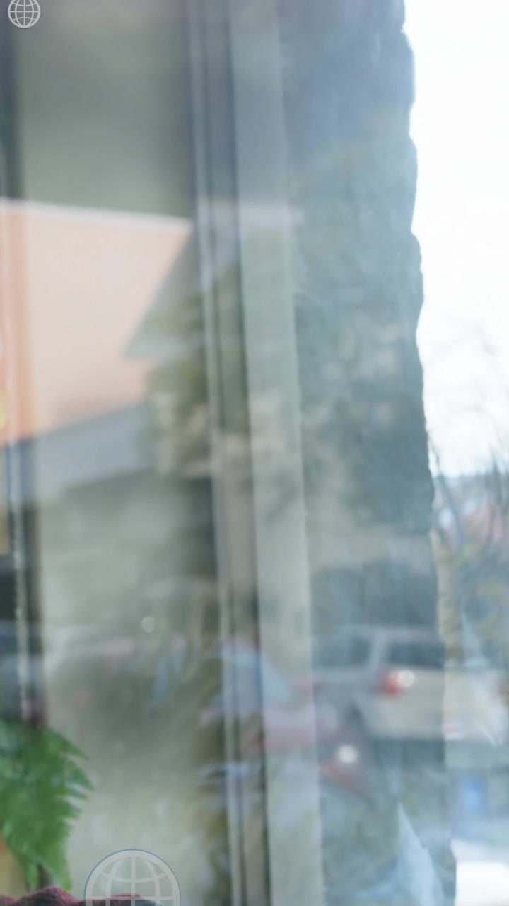 Animation of globe icons over man drinking coffee while looking through glass window