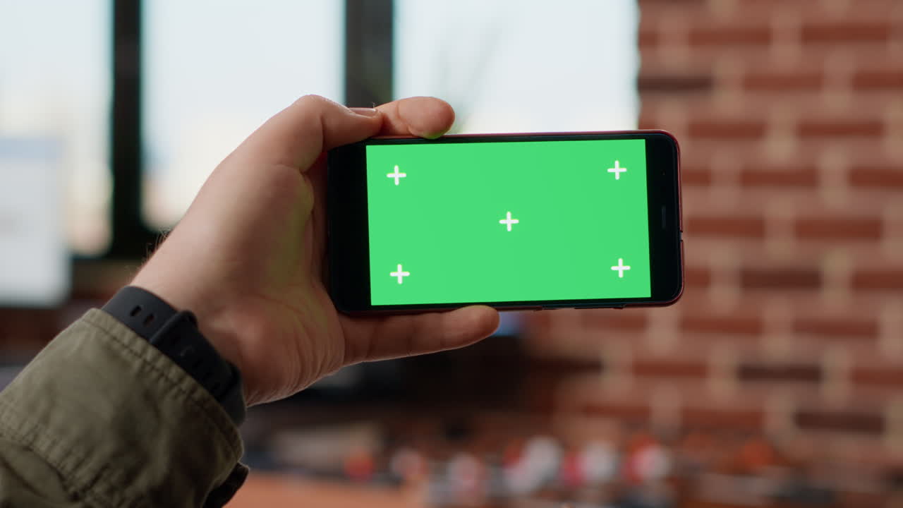 Business manager holding horizontal greenscreen on smartphone