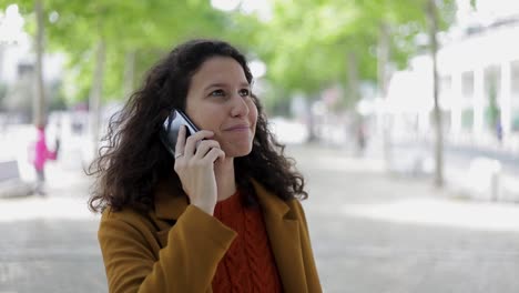 Lächelnde-Junge-Frau,-Die-Draußen-Mit-Dem-Handy-Spricht