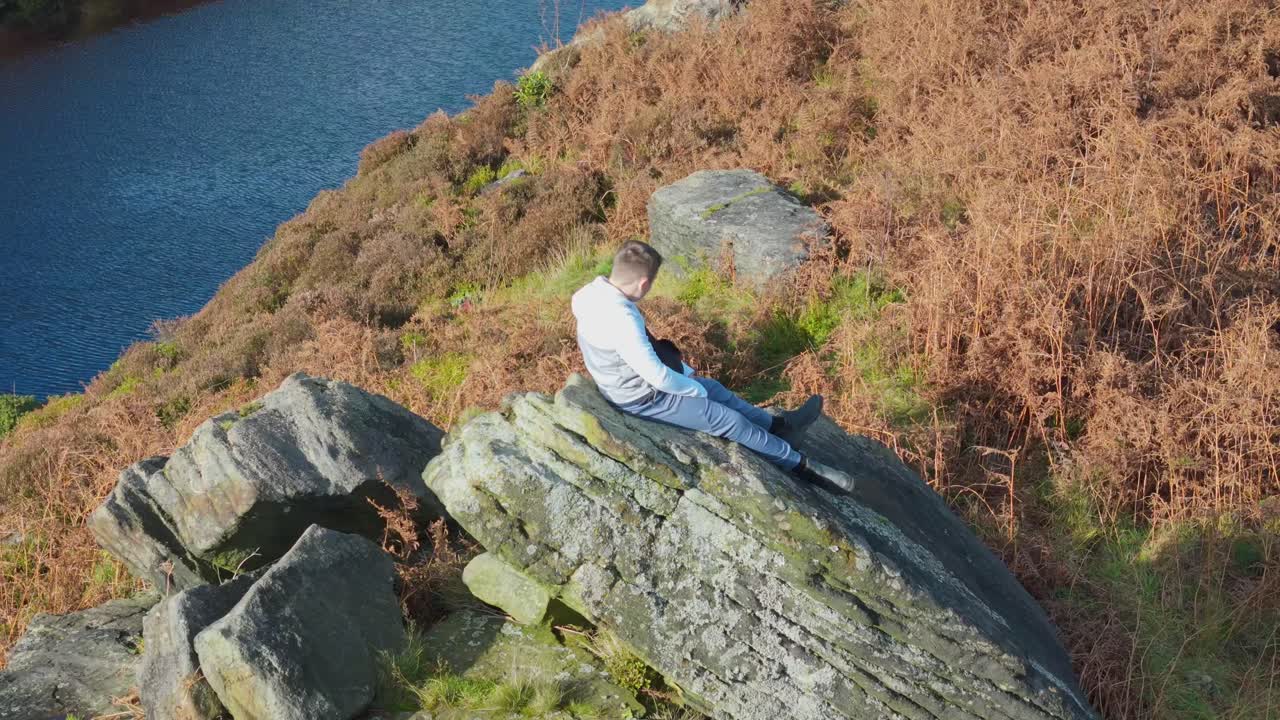 공중 비디오는 부드럽게 무어랜드 설정에서 거대한 바위 표면에 자리 잡은 사려 깊은 어린 소년을 공전합니다.
