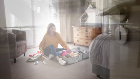 animation of happy caucasian woman packing suitcase in bedroom over travellers wheeling suitcases