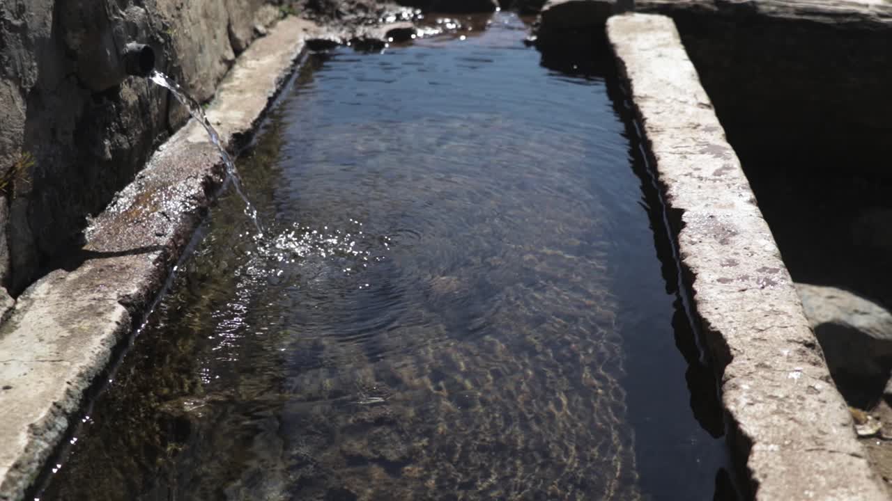 Person drinking water with hands from a natural well. Fresh water.