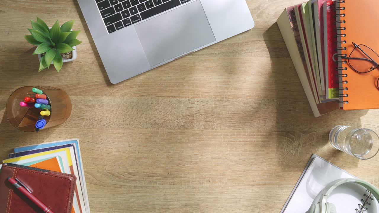 초록색 화면을 모방한 노트북 컴퓨터의 상단에서 아래로 볼 때, 펜, 안경, 그리고 물 한 잔을 가진 노트북 에 나무 사무실 책상 위에 크로마키 디스플레이가 있습니다.