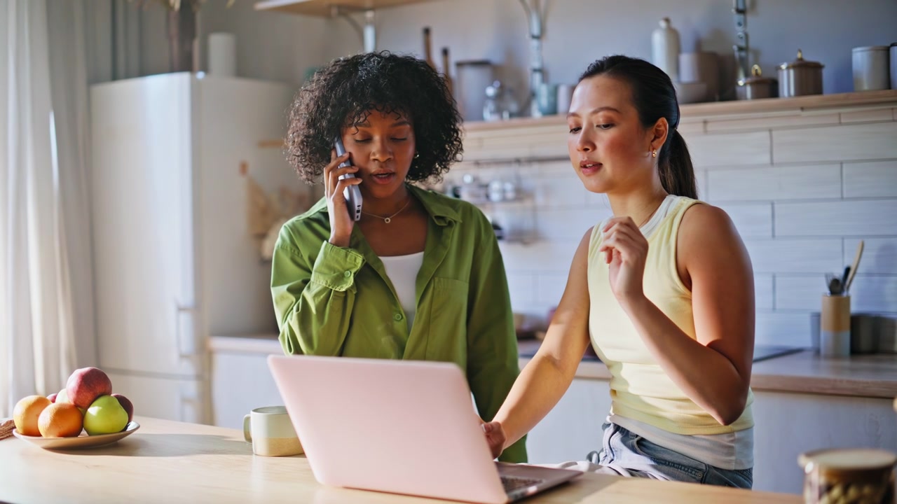 Women working home kitchen with laptop phone. Business partners discuss online.