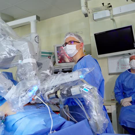 innovative equipment with robotic arms doing surgery. medical robot doing an operation on a patient in modern clinic. doctors in medical uniform observe the work of robotic system