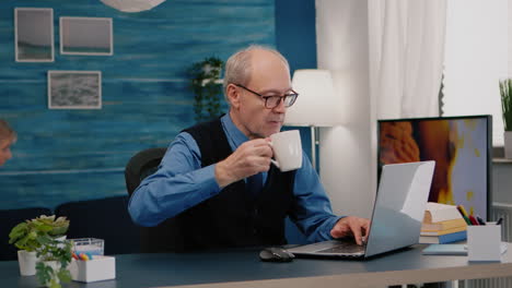 focused old entrepreneur checking graphics writing on laptop