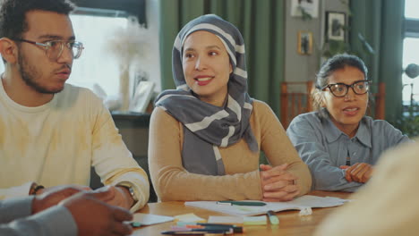 muslim woman in hijab listening to teacher and group mate on english class