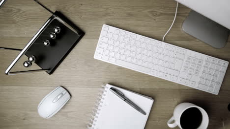 Overhead-of-newtons-cradle-toy-swinging-on-office-desk