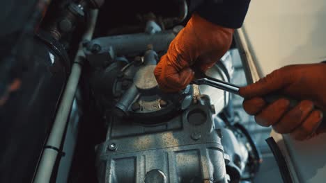 Mechaniker-Mit-Orangefarbenen-Handschuhen-Bindet-Schrauben-Mit-Einem-Schraubenschlüssel-Einer-Abdeckung-Von-Einem-Kleinen-Motor-Fest