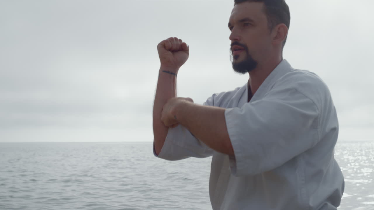 deportista centrado en el entrenamiento de karate en la playa de cerca. mman entrenando artes marciales