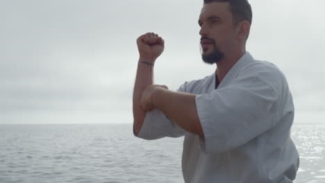 focused sportsman workout karate on beach close up. mman training martial arts