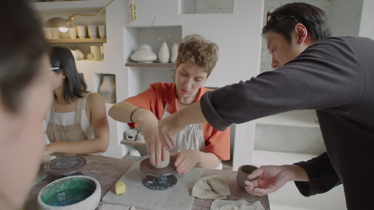 Asian Ceramist Teaching Student How to Use Pottery Wheel