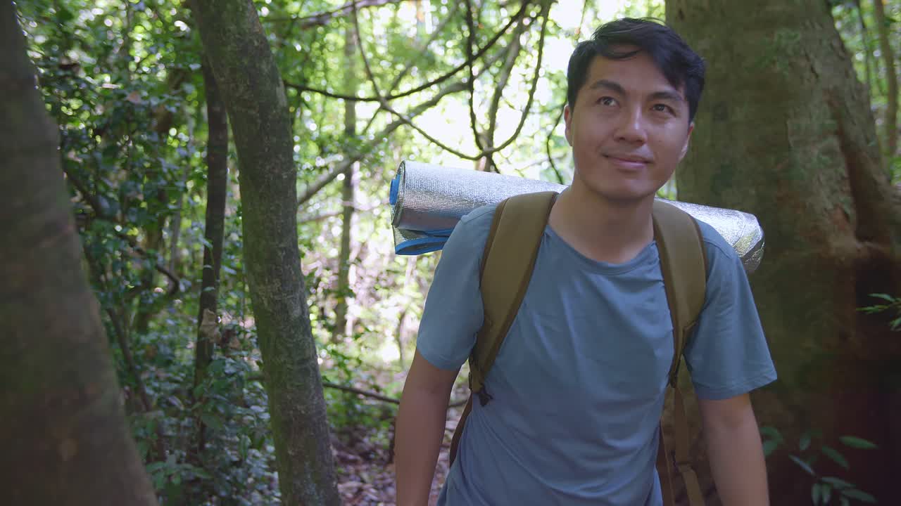 hombre excursionista asiático con una mochila caminando en el bosque