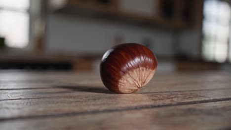 Close-up video shot of a chestnut on a wooden table, capturing rich textures and natural light