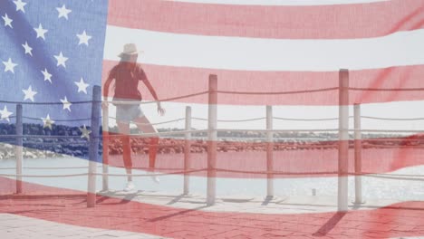 american flag waving against caucasian woman wearing a hat climbing over the wooden pier fence