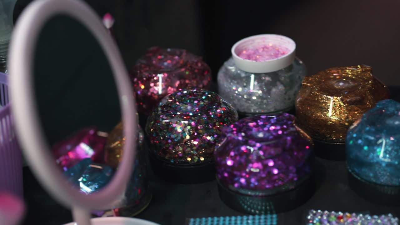 Colorful glitter jars displayed at a beauty festival, bright and shiny
