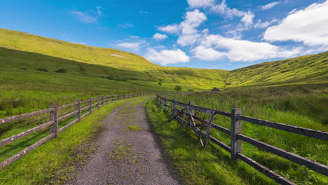 timelapse of a remote hillside farming grassland with walk path along the fence on sunny day with moving clouds casting shadows on the land in county sligo in ireland