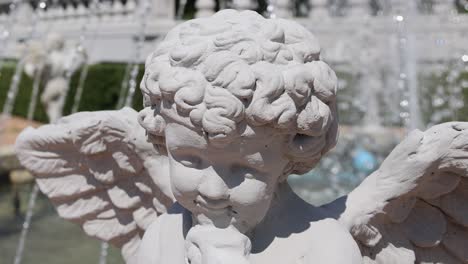 close-up of a cherub statue with dynamic fountain background