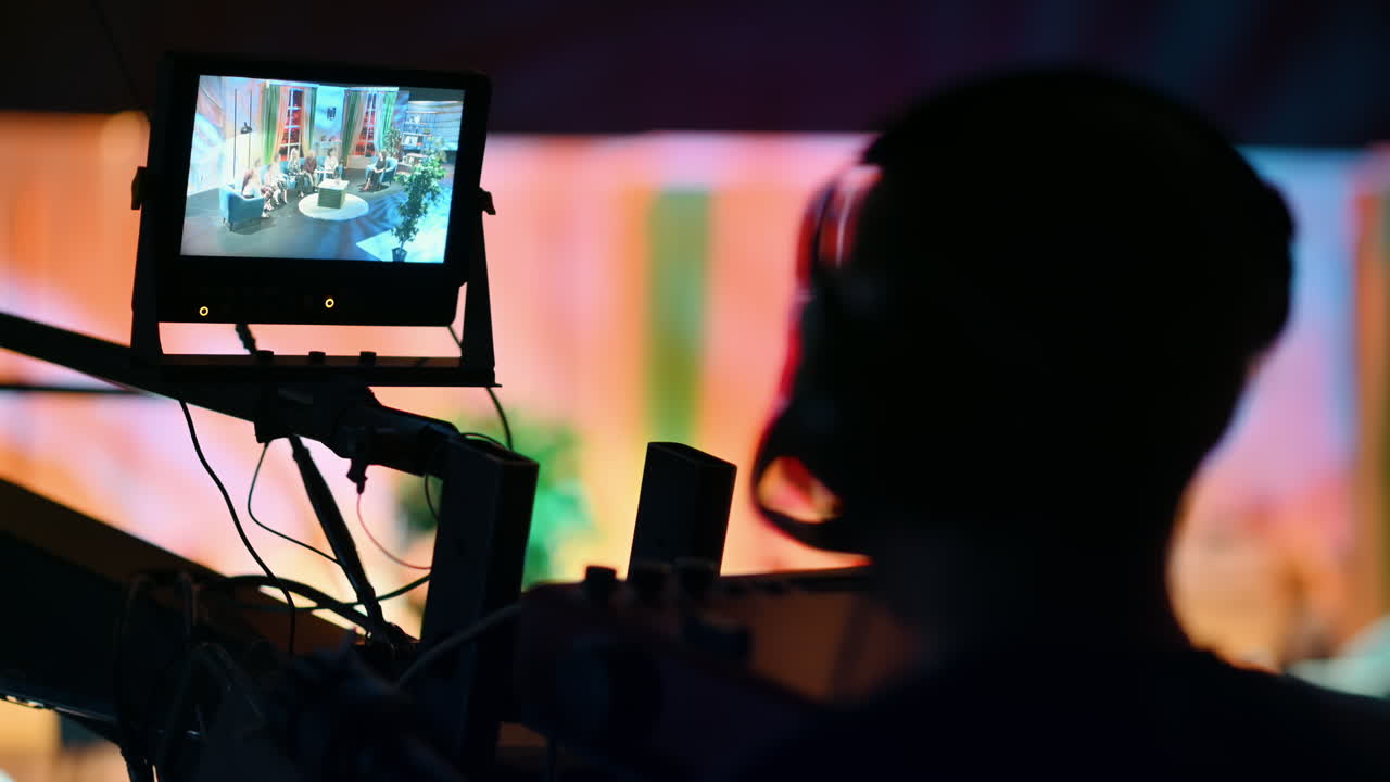 Cameraman filming a television talk show on a professional camera mounted on the crane. Video production backstage in a dark studio