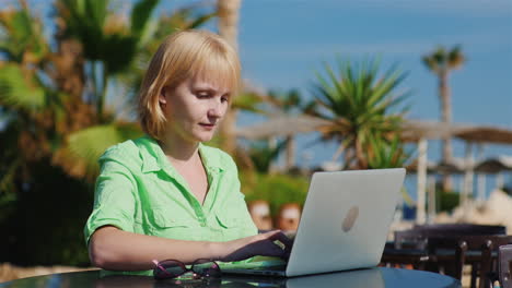 Frau-Tourist-Tippt-Auf-Einem-Laptop-Vor-Dem-Hintergrund-Mediterraner-Erholungsgebiete