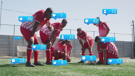 Animation-of-social-media-icons-over-tired-diverse-male-soccer-players-taking-break-on-sports-field