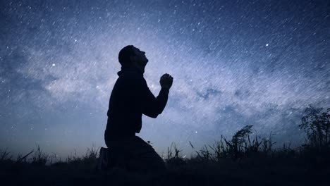 man praying under a starry night