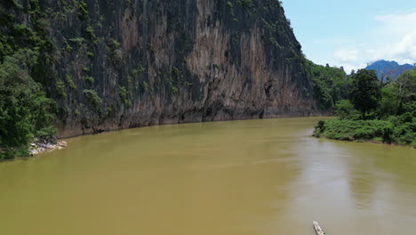 los barcos de pesca locales palidecen en comparación con los impresionantes acantilados del río mekong en laos.