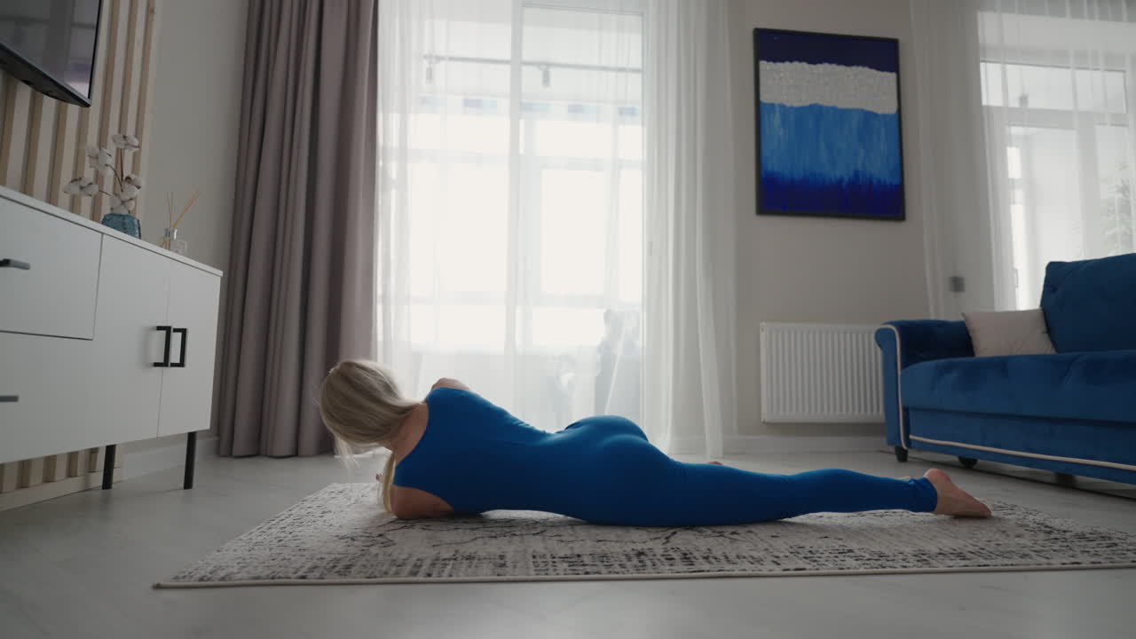 여성은 아파트의 카 ⁇ 에 집에서 훈련합니다. 집에서 운동을 수행합니다. 피트니스 스트레칭과 요가가 집에서 원격으로. 원격 훈련과 건강한 생활 방식