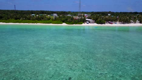 amplio movimiento aéreo a lo largo de la costa de maldivas que muestra una hermosa playa, agua turquesa y pueblo