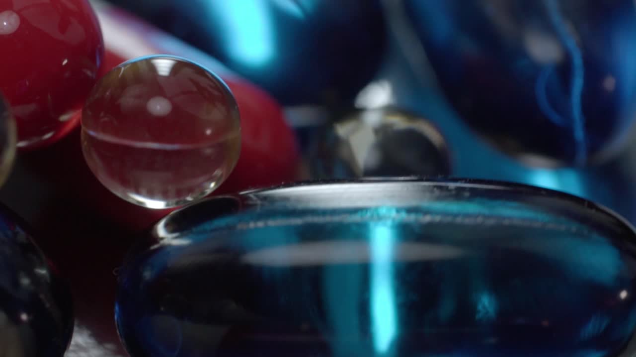 Macro close up of assorted medicine capsules and gel pills on reflective surface, healthcare concept
