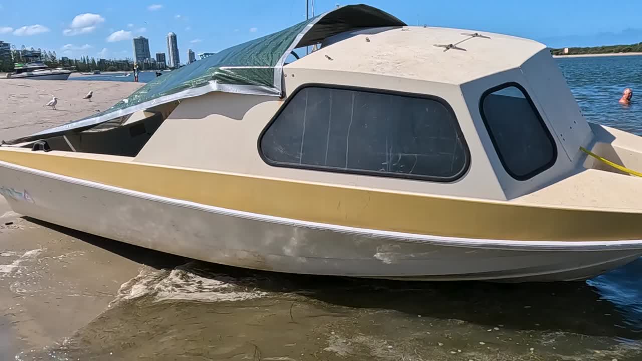 Un classico motoscafo giallo e bianco si trova sulla riva sabbiosa sotto un cielo luminoso