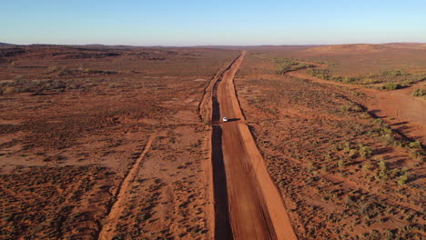 aerial: drone shot following a vehicle at height but moves closer to the vehicle as it drives further along the outback road, in broken hill, australia