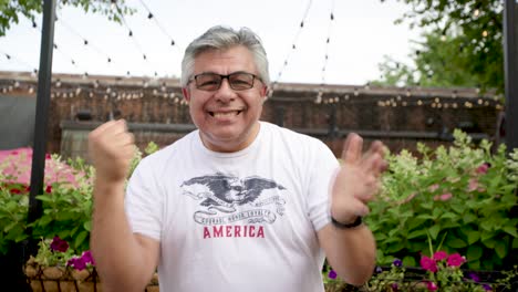 hombre con gafas celebra con puños en el aire afuera en cámara lenta