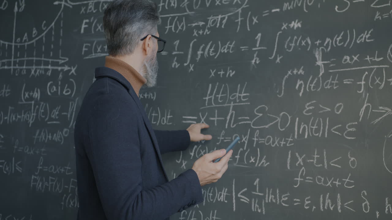 Professor using smartphone in front of chalkboard with mathematical equations