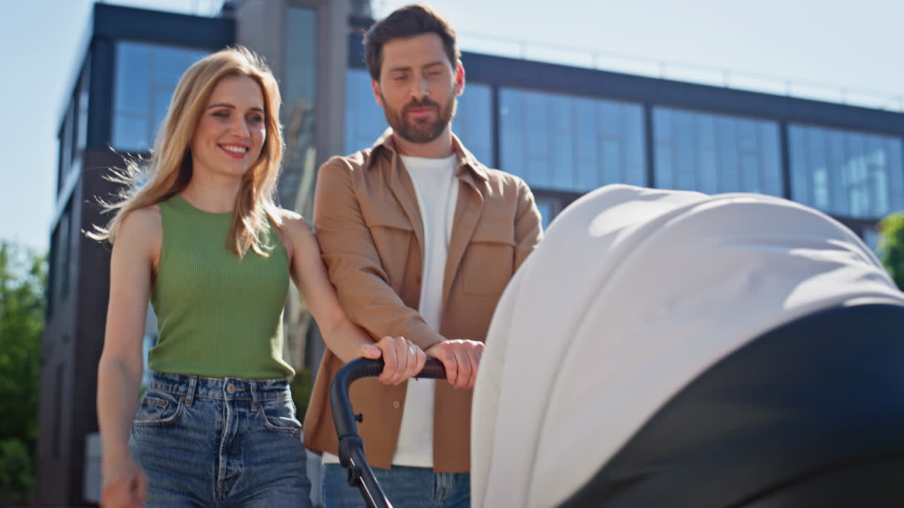 Parents legs walking newborn baby in stroller in street morning sunlight closeup